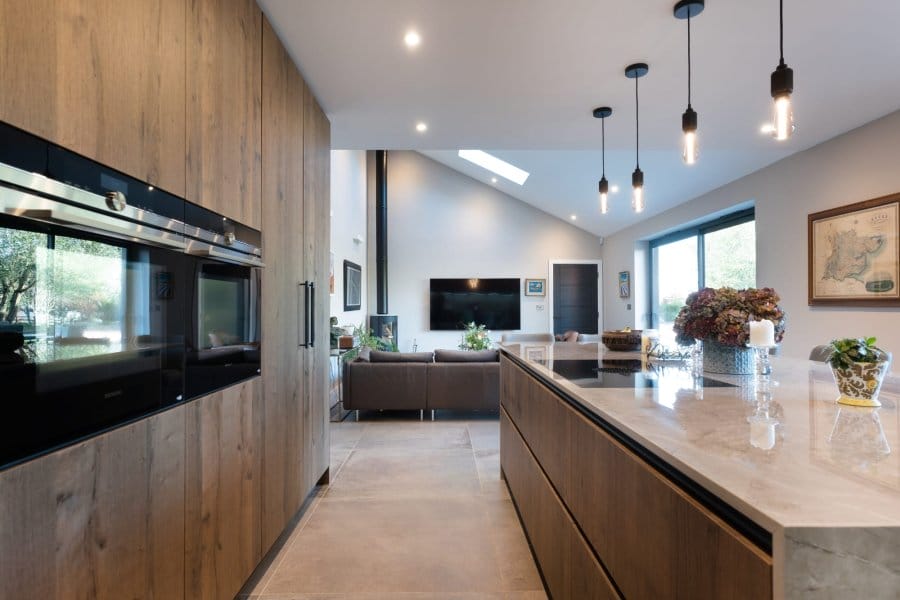 Handleless kitchen with dark wood cabinets and white marble countertops