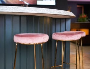 Pink upholstered bar stools with brass legs/detailing