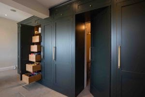 Bespoke green cabinetry with a hidden utility room door and drawers.