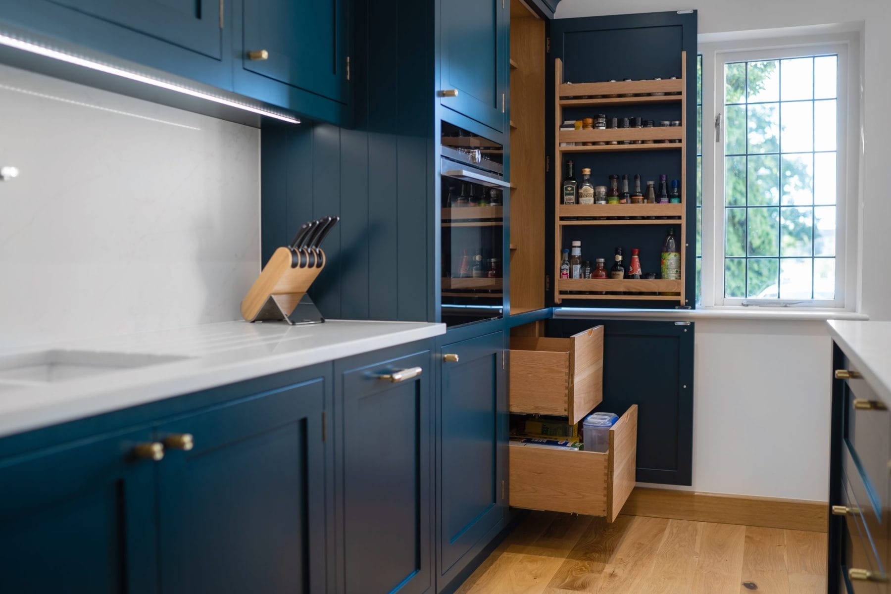 dark blue shaker kitchen with oak dovetailed pantry drawers and brushed brass knurled kitchen handles