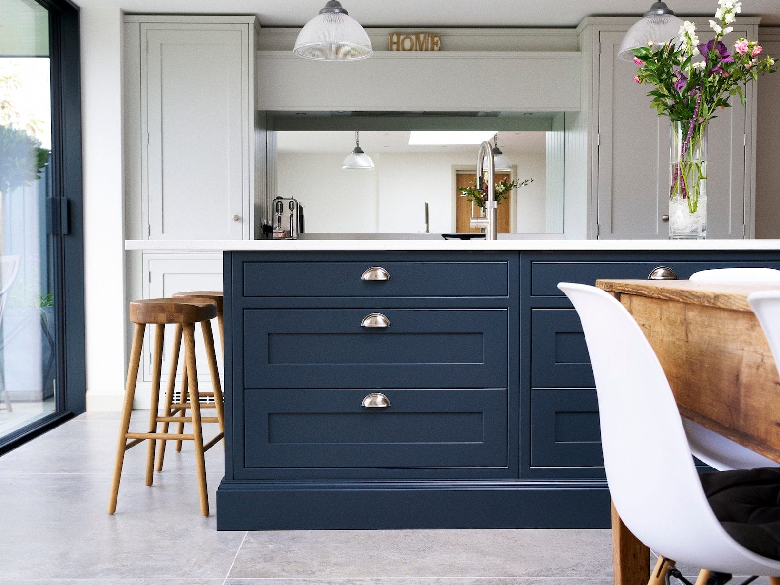 open plan in frame shaker kitchen with dark blue island and neutral tall cabinetry