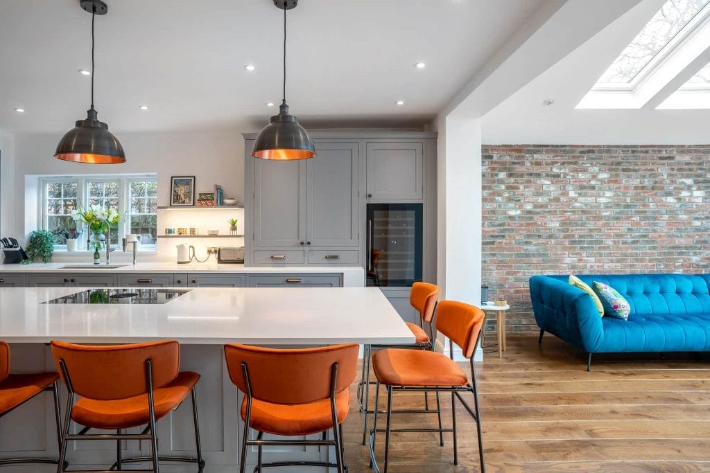 Large kitchen with island, orange chairs, and hanging lighting.