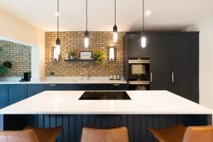 Dark blue shaker kitchen with island and brown bar stools - Down lighting industrial look