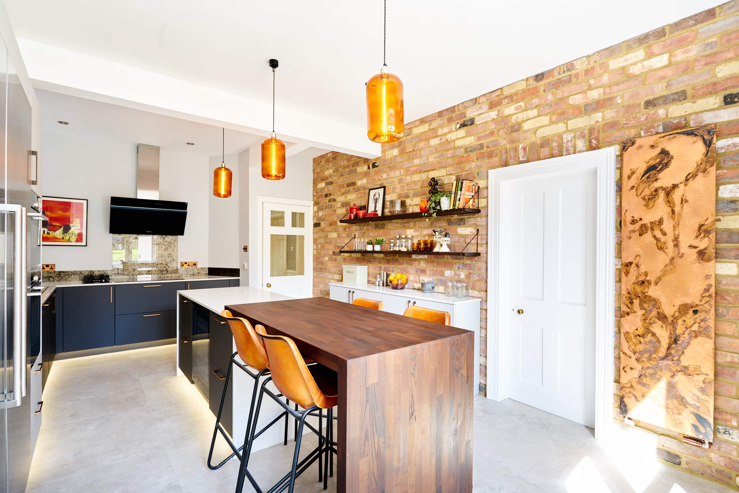contemporary kitchen with copper radiator, exposed brickwork and breakfast bar attached to island