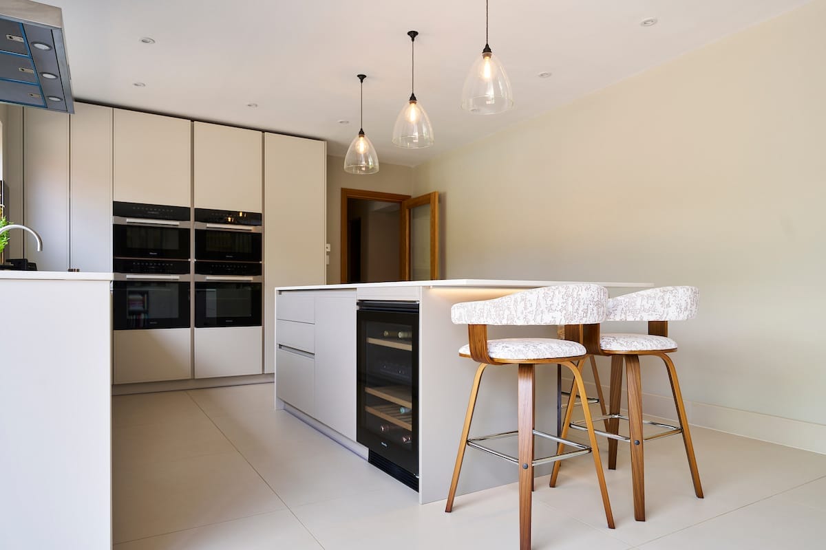 Marble-effect kitchen island with grey modern handless cabinets, used for food prep and informal dining.