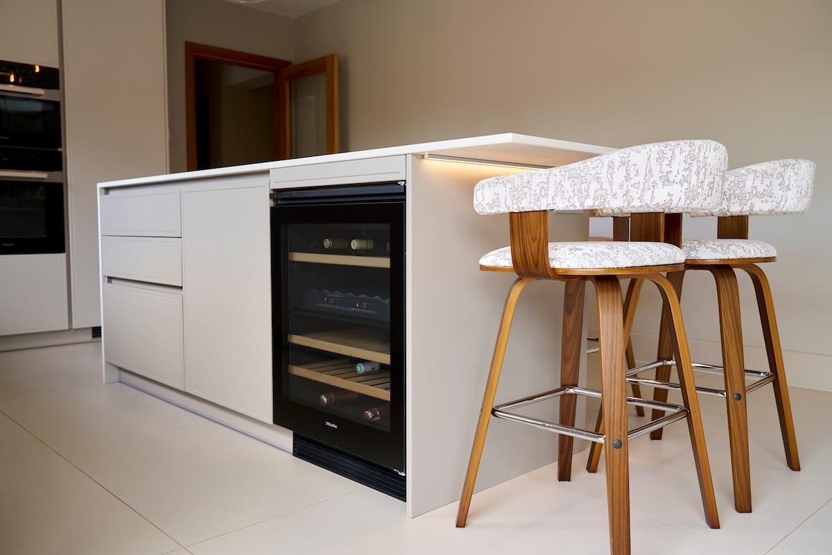 Intergrated wine cooler within the marble effect kitchen island being used a breakfast bar with wooden bar stools