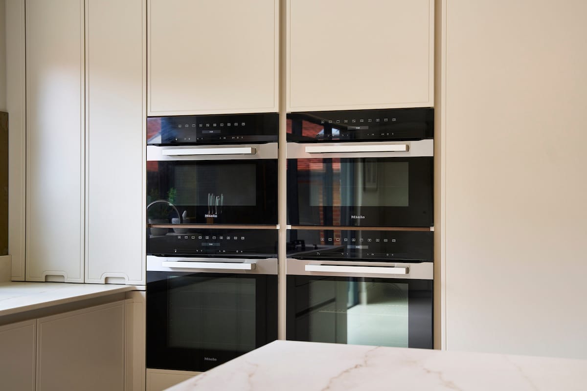 Integrated Miele appliances concealed within full-height handleless cabinetry for a seamless look.