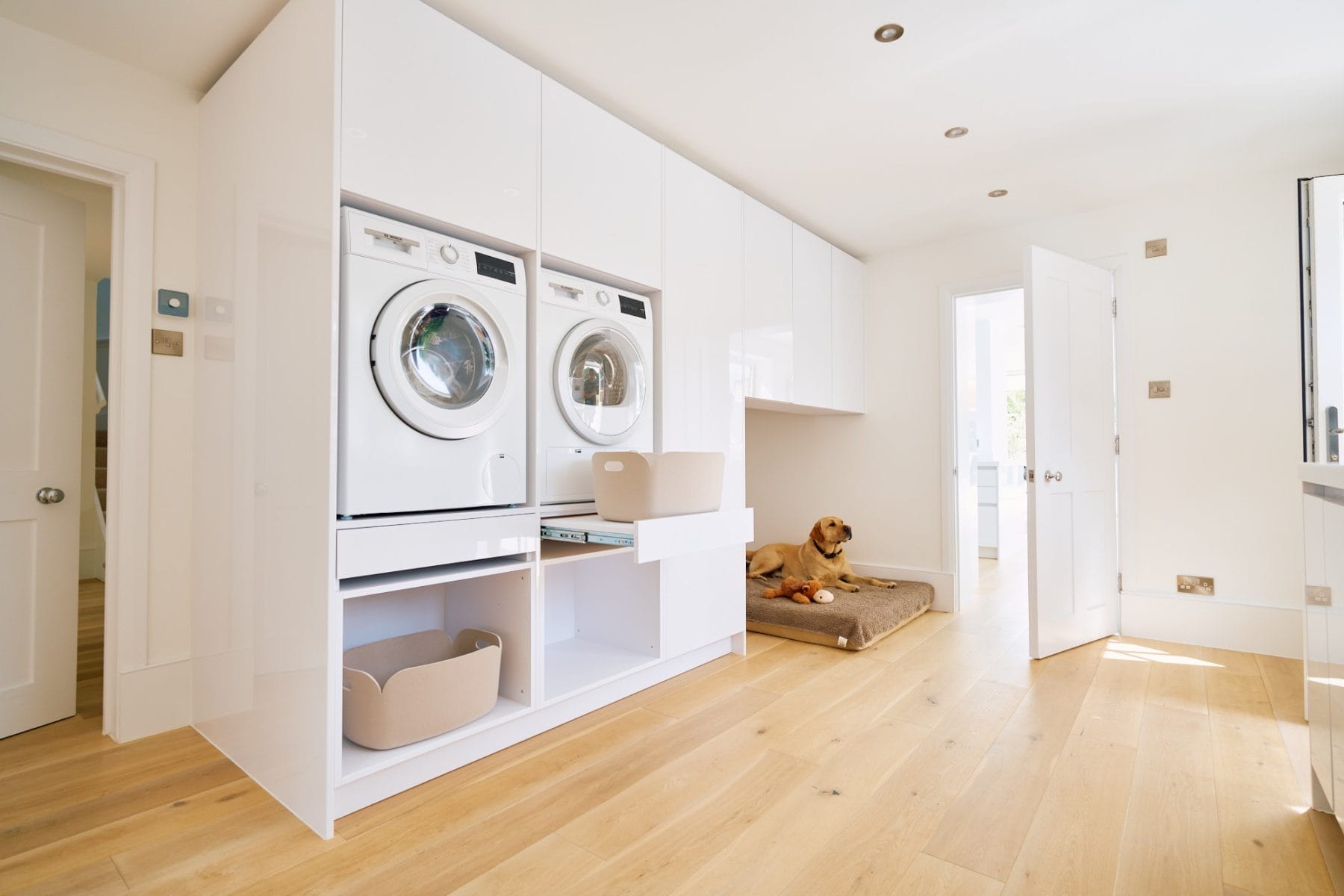 Minimalist handleless kitchen, Spacious utility room with stacked washer and dryer, pull‑out laundry shelf and built‑in dog bed area.