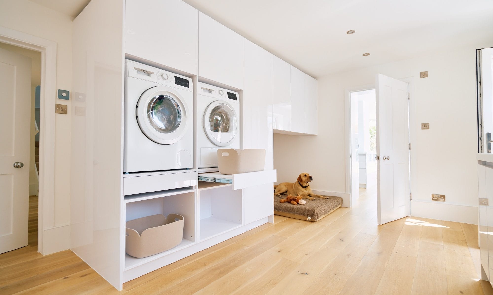 Minimalist handleless kitchen, Spacious utility room with stacked washer and dryer, pull‑out laundry shelf and built‑in dog bed area.